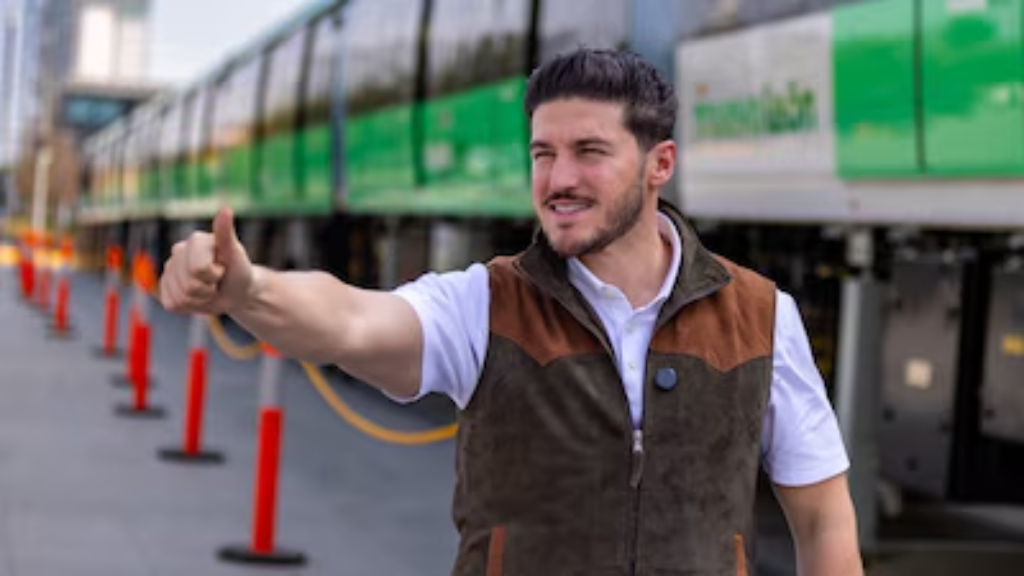 Man in a Brown Vest and White Shirt Gives a Thumbs-up Near a Green Train at a Construction Site › Regiadísticas