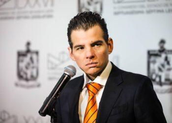 Man in a Dark Suit with an Orange Striped Tie Speaks into a Microphone at a Conference or Event. › Regiadísticas